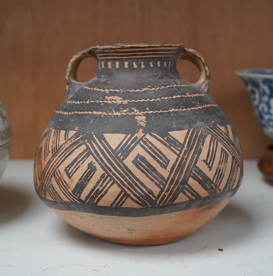 A Chinese neolithic pottery two handled jar - 14cm tall. Condition - fair to good, Provenance: the vendor‘s parents lived in Hong Kong from 1947 and bought the jar from a specialist dealer before 1980.